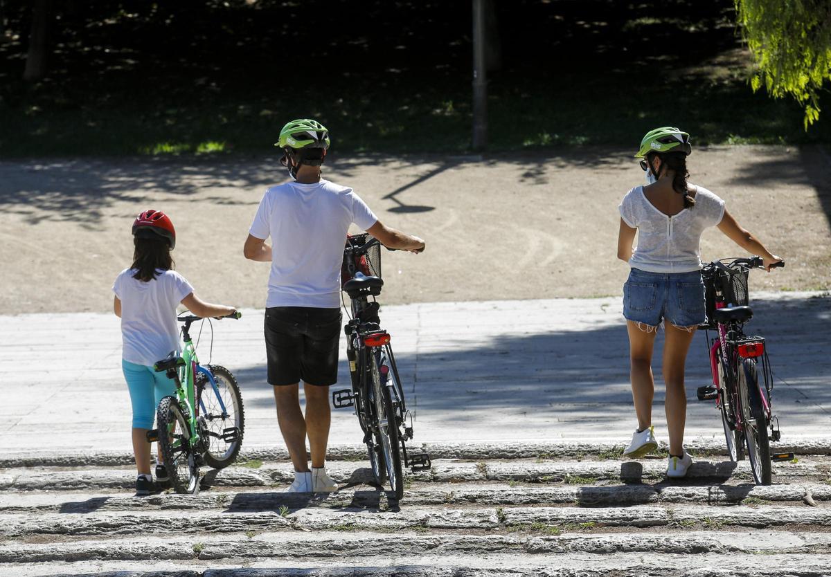 Niños con una bicicleta transitando por un parque.
