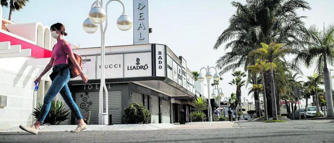 Una mujer pasa ante un centro comercial de primeras marcas, cerrado por la pandemia, en el sur de Tenerife. | | CARSTEN W. LAURITSEN