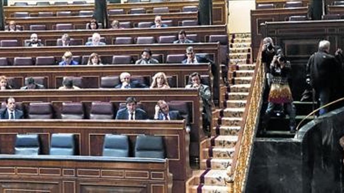 La ministra de Sanidad, Ana Mato, se dirige al hemiciclo del Congreso mientras los asientos reservados a los demás miembros del Gobierno permanecen vacíos, ayer.