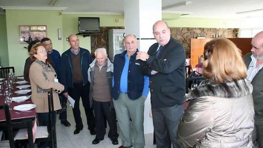 Juan Vega, tercero por la derecha, hablando con los vecinos de Ferrera, ayer, en el bar Fano de la localidad.