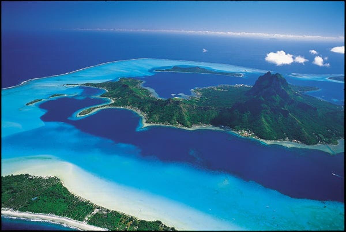 Motu Tofari (Bora Bora, Polinesia Francesa). Océano Pacífico Pocos lugares existen en el mundo como la Polinesia Francesa para evocar playas exóticas y tropicales de los Mares del Sur; y pocos lugares hay también tan románticos para celebrar una luna de miel o un viaje realmente especial. La playa del Motu Tofari, uno de los islotes coralinos que rodean el atolón de Bora Bora, representa el súmmum de este concepto: íntima, silenciosa y escondida, con apenas un puñado de bungalós que se levantan literalmente encima del agua de la laguna. El Océano Pacífico es aquí tan atrevido que no hace falta ponerse las gafas para poder admirar los peces de colores que viven en este privilegiado hábitat. Para contemplar rayas, tiburones y todo tipo de corales se pueden realizar desde paseos en canoa, barca o barcos con suelos de cristal hasta inmersiones de buceo para todos los niveles o paseos con escafandras. Compras: además de la típica artesanía local elaborada en madera, nácar y esencias, el principal souvenir que se puede comprar en Bora Bora son sus exóticas y cotizadas perlas negras. El lugar ideal para hacerlo es Vaitape, su principal localidad. www.tahiti-tourisme.com   En la foto: La playa del Motu Tofari, uno de los islotes que rodean el atolón de Bora Bora, es íntima y silenciosa, con un puñado de bungalós que se levantan literalmente sobre el agua de la laguna.