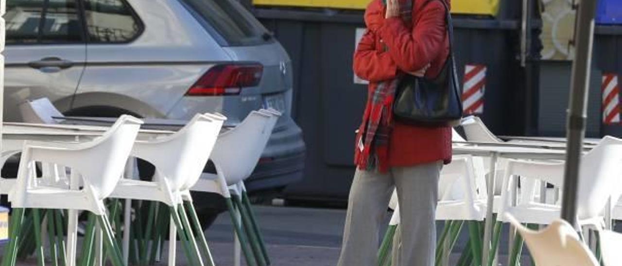 Una mujer que paseaba ayer por una calle alcireña se tapa con una bufanda para protegerse del frío.