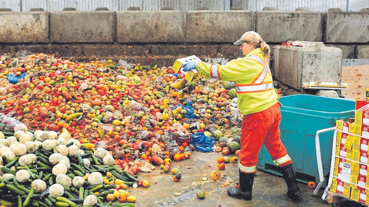 Una empleada llençant grans quantitats d’aliments.