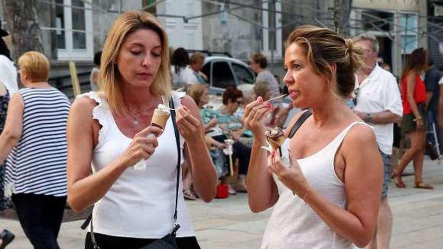 Dos mujeres aplacan el intenso calor tomando un helado, ayer por la tarde en el centro de Vigo. // Marta G. Brea