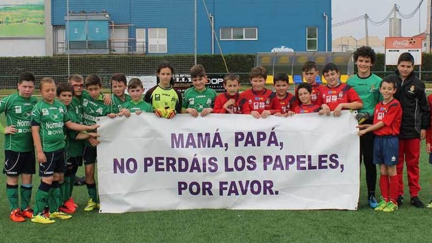 Jugadores del Astur y del Colloto muestran una pancarta antes de su partido en el torneo alevín de Semana Santa de El Berrón.