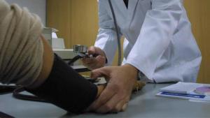 Un médico mide la tensión a un paciente en la consulta.