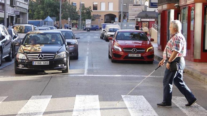 Una persona invidente cruza sola la calle Juan Fernández por un paso de peatones mientras los vehículos están parados.