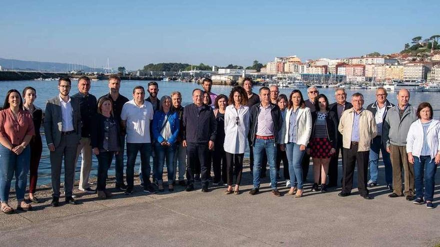 La práctica totalidad de los miembros de la candidatura del PP de Cangas se fotografió ayer en Ojea, con el puerto al fondo. // G.Núñez