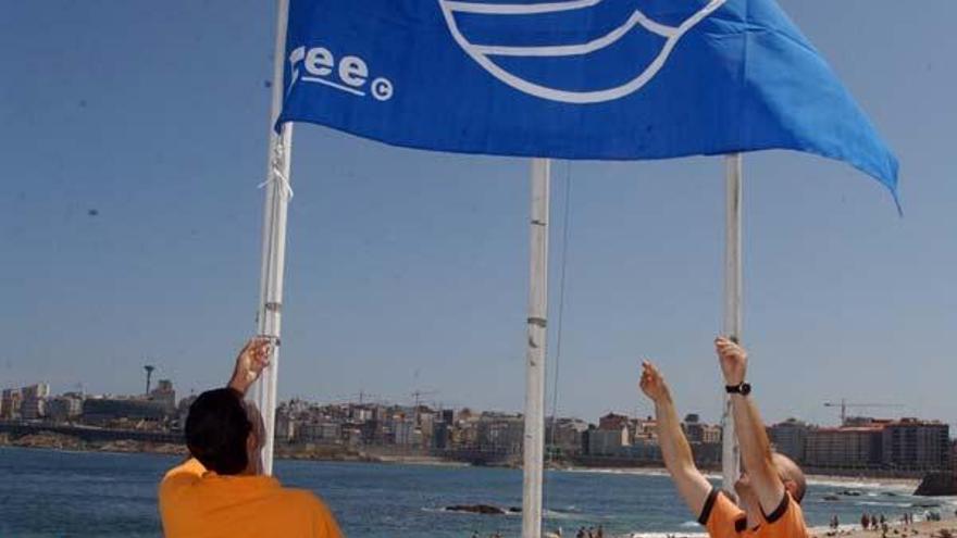 Dos agentes de Protección Civil colan la bandera en una playa gallega.