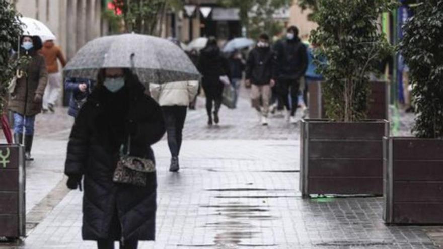 Una mujer pasea con un paraguas por el centro de Palma. | MANU MIELNIEZUK