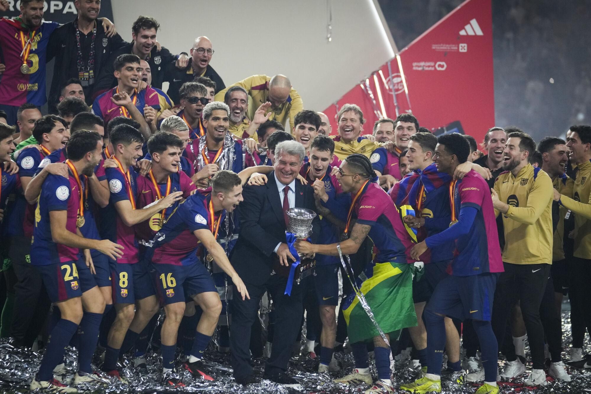 President of Barcelona Joan Laporta, centre, and his players celebrate with the trophy after winning the Spanish Super Cup against Real Madrid at King Abdullah Stadium in Jeddah, Saudi Arabia, Monday, Jan. 13, 2025. (AP Photo/Altaf Qadri)