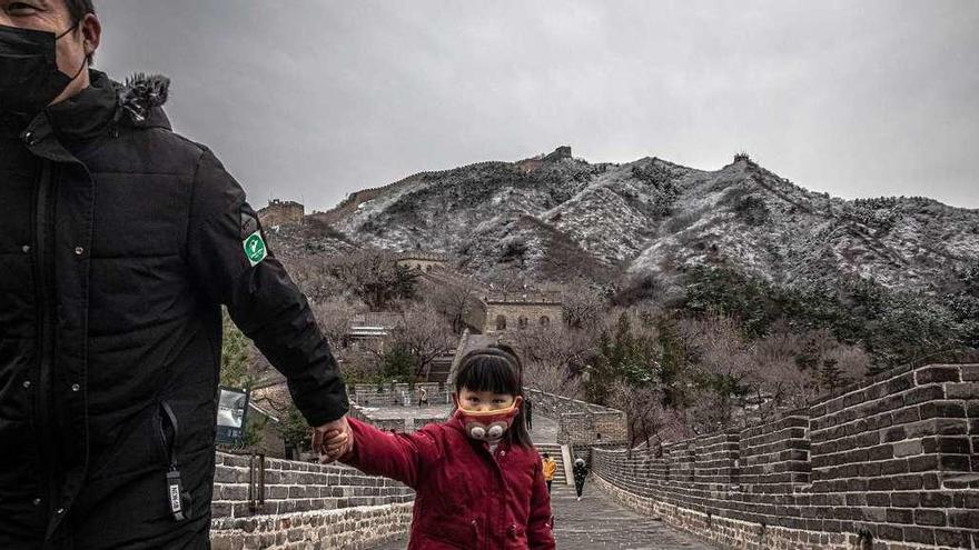 Una niña con mascarilla, ayer en la Gran Muralla china, en Pekín. // R. Pilipey