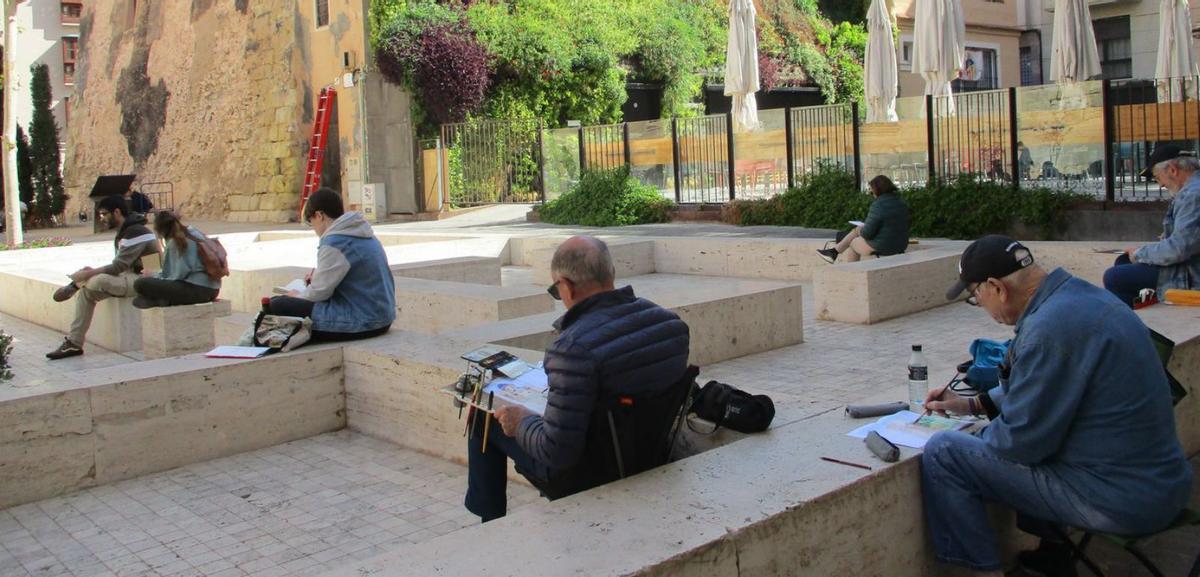 A la izquierda, la exposición de los trabajos realizados en la última edición; y, a la derecha, algunos de los participantes el pasado año.