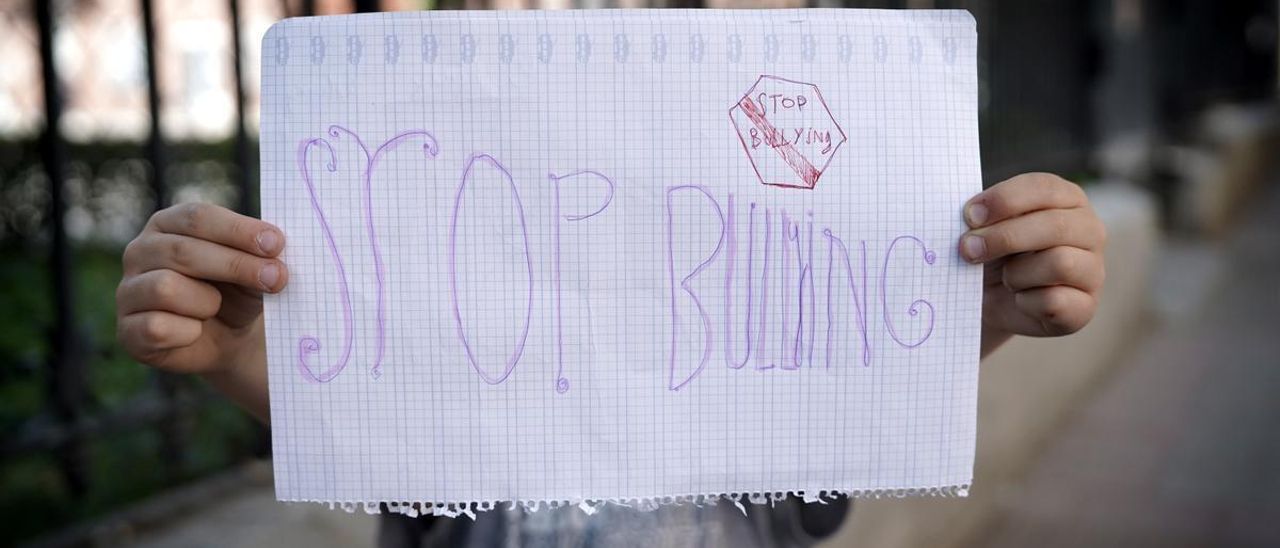 Un niño con un cartel de stop bullying.
