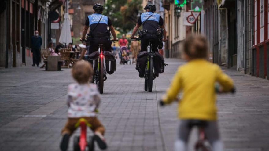 Los agentes por la calle de La Carrera, seguidos por unos niños también en bicicleta