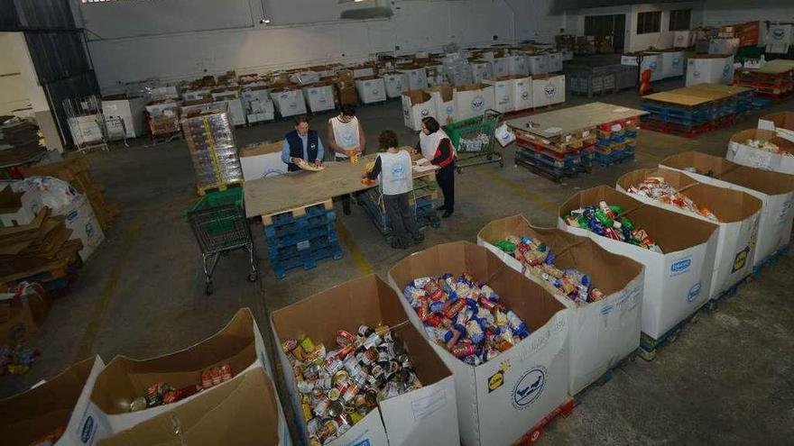 Voluntarios del Banco de Alimentos organizando productos en su almacén en la Avenida de Lugo. // G.S.