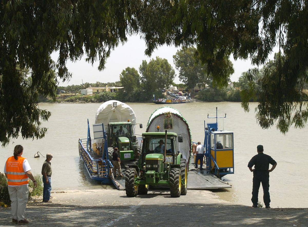 Carretas de una hermandad del Rocío cruzan el Rio Guadalquivir en la barcaza de Coria del Rio.