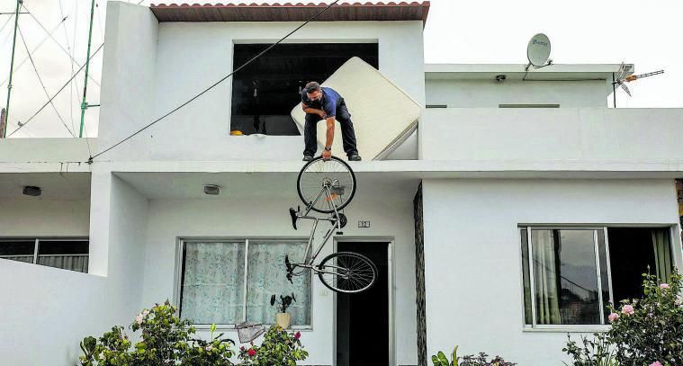 Un hombre saca su bicicleta por la ventana
en el desalojo de su vivienda. | // KIKE RINCÓN / E.P.