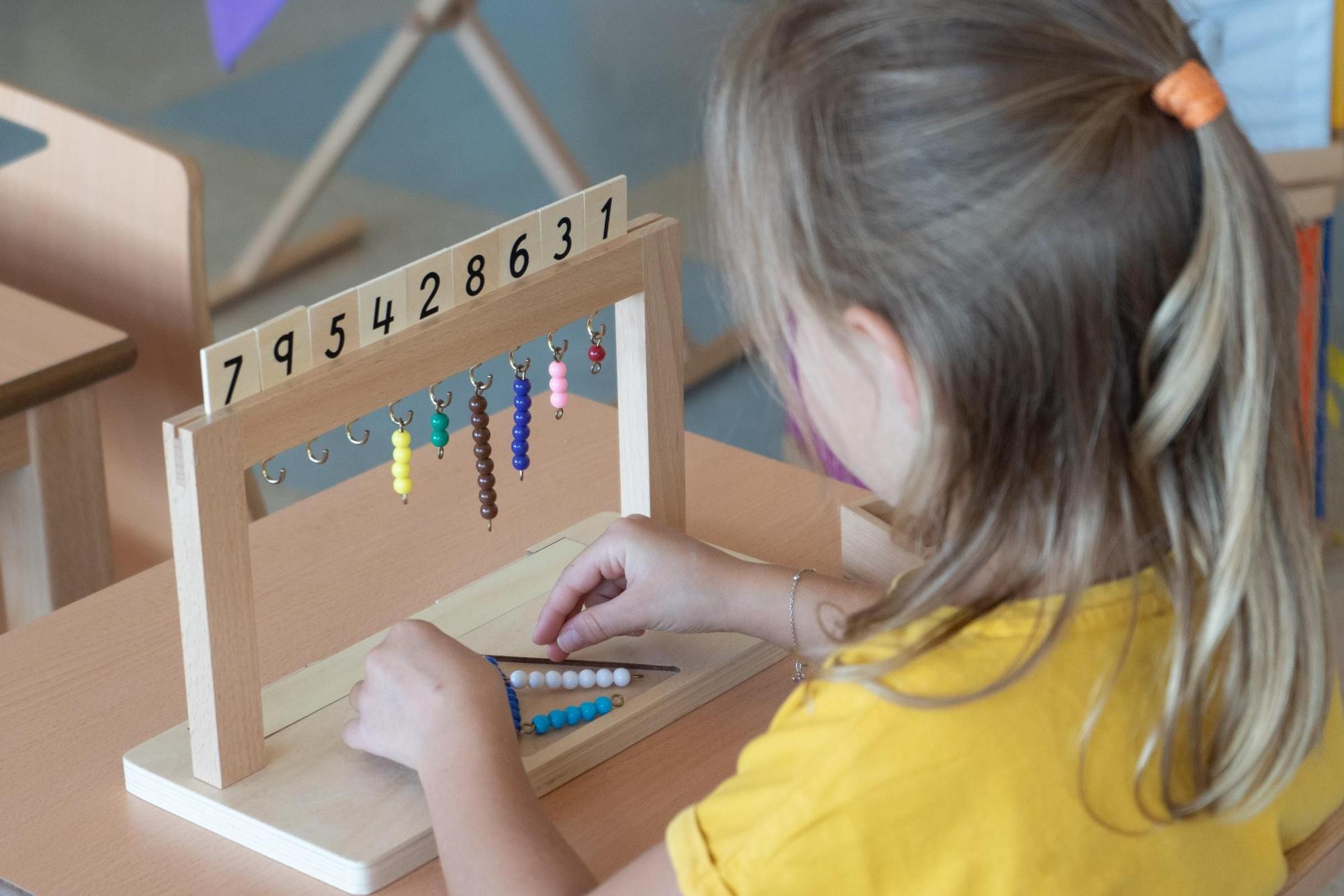Una niña aprende los números con el colgador de perlas