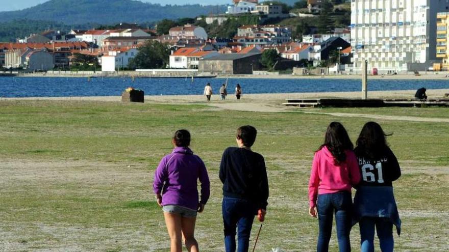 Unos jóvenes disfrutan de un inmejorable tiempo otoñal en la playa Compostela. // Iñaki Abella