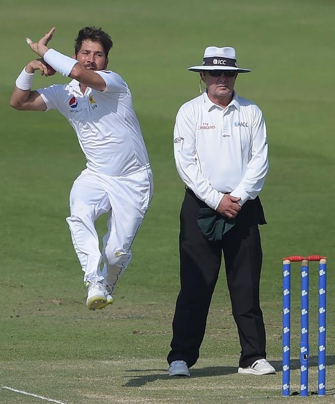 El paquistaní Yasir Shah (L) entrega el balón durante el tercer día del primer partido de críquet de prueba entre Pakistán y Nueva Zelanda en el Sheikh Zayed International Cricket Stadium en Abu Dhabi.