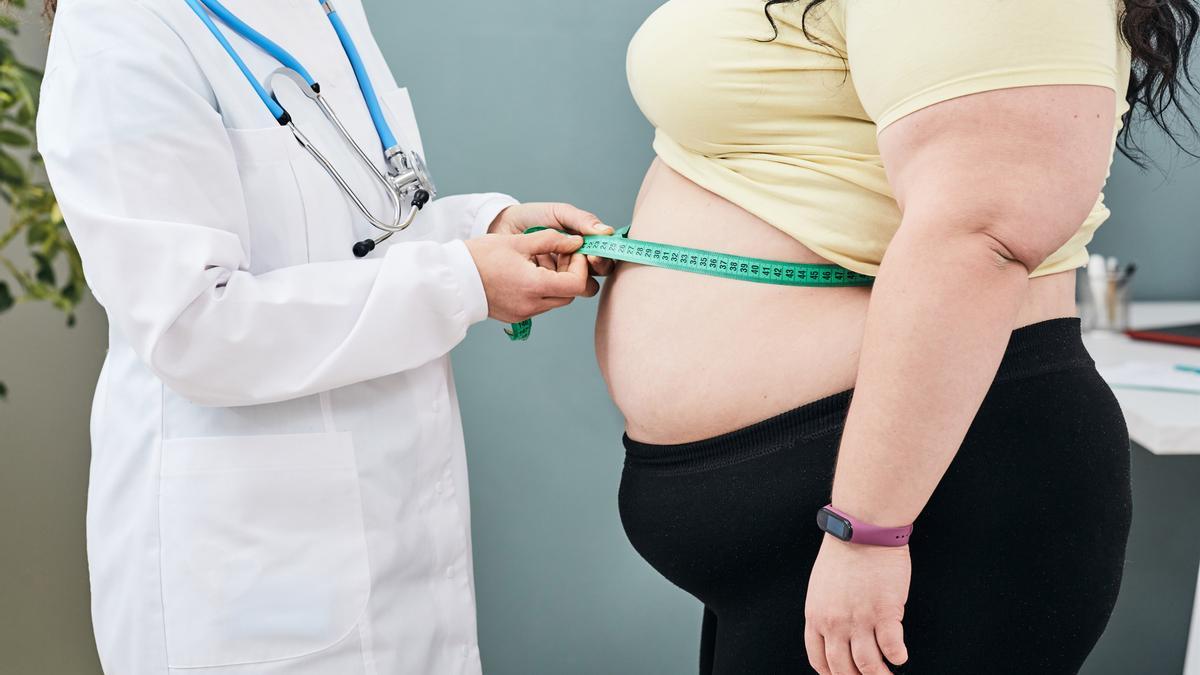 Una médica mide a una paciente con obesidad.