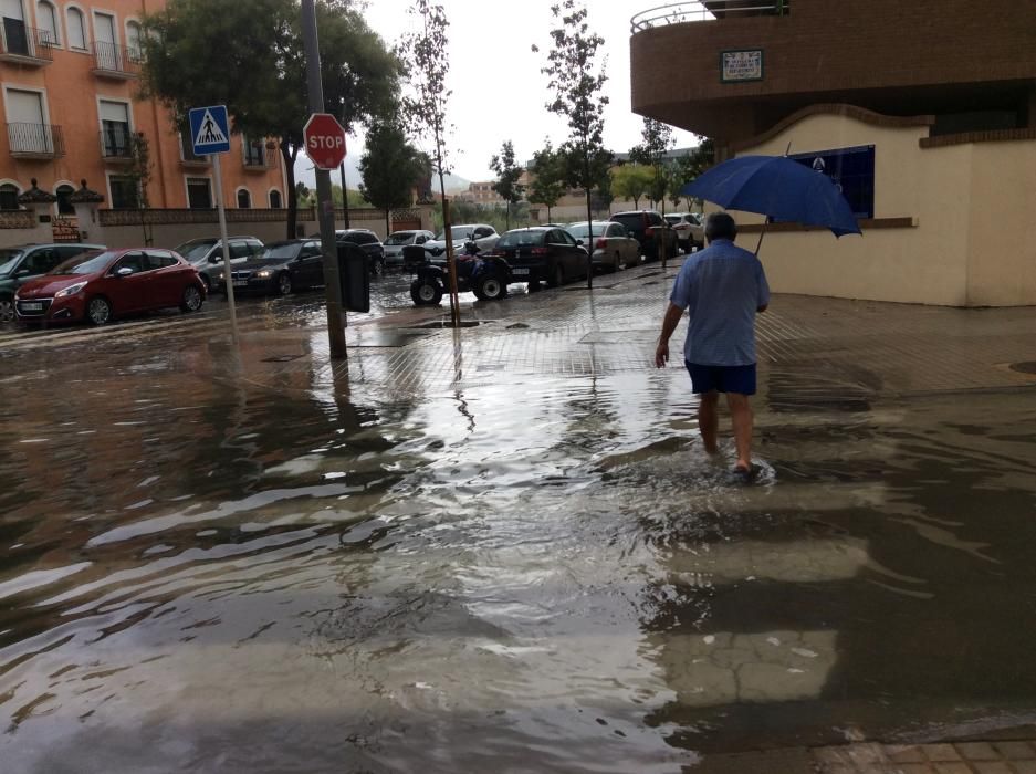 Los peatones tratan de cruzar por las calles anegadas de agua en Dénia.