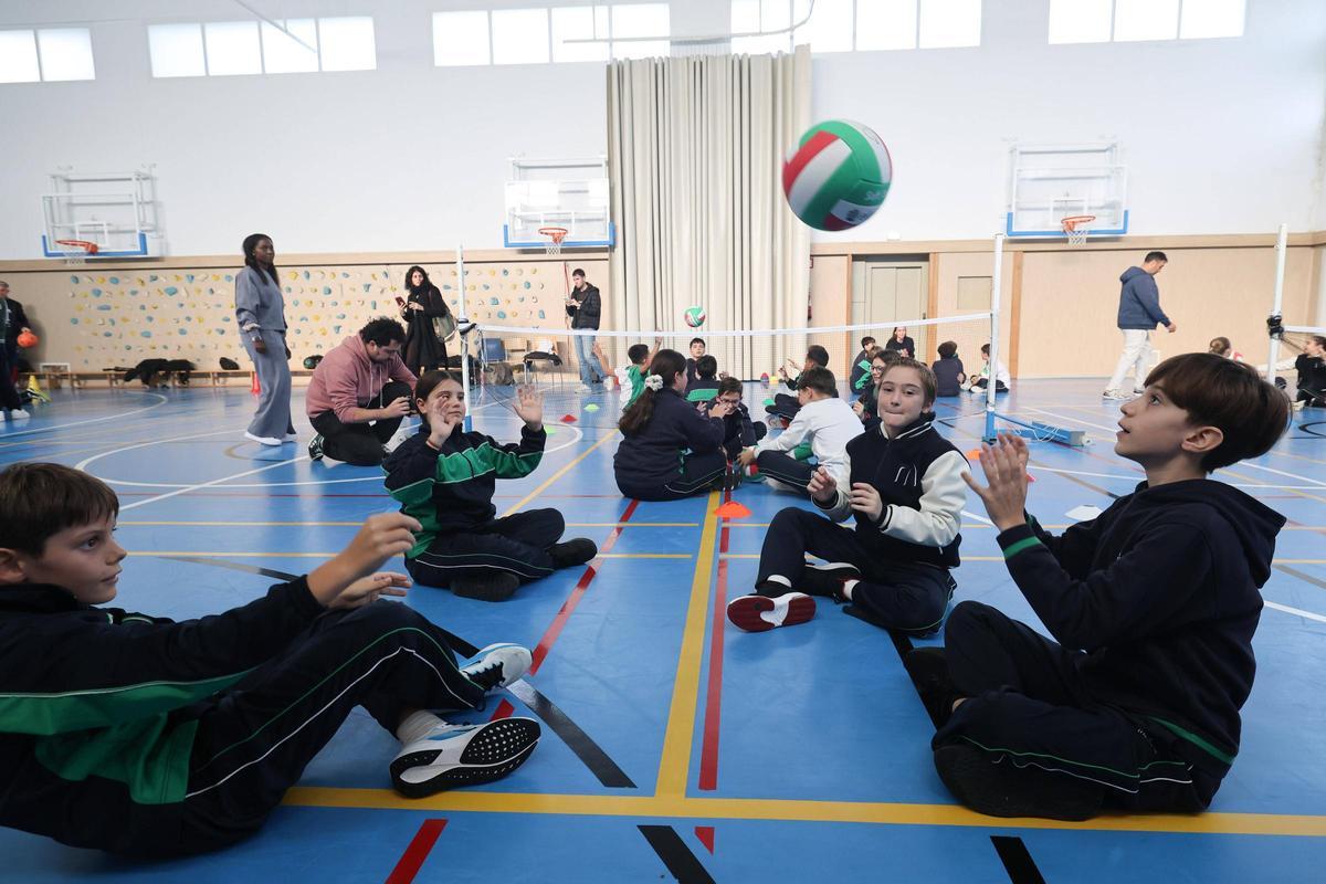 Las y los alumnos jugando a voleibol sentados
