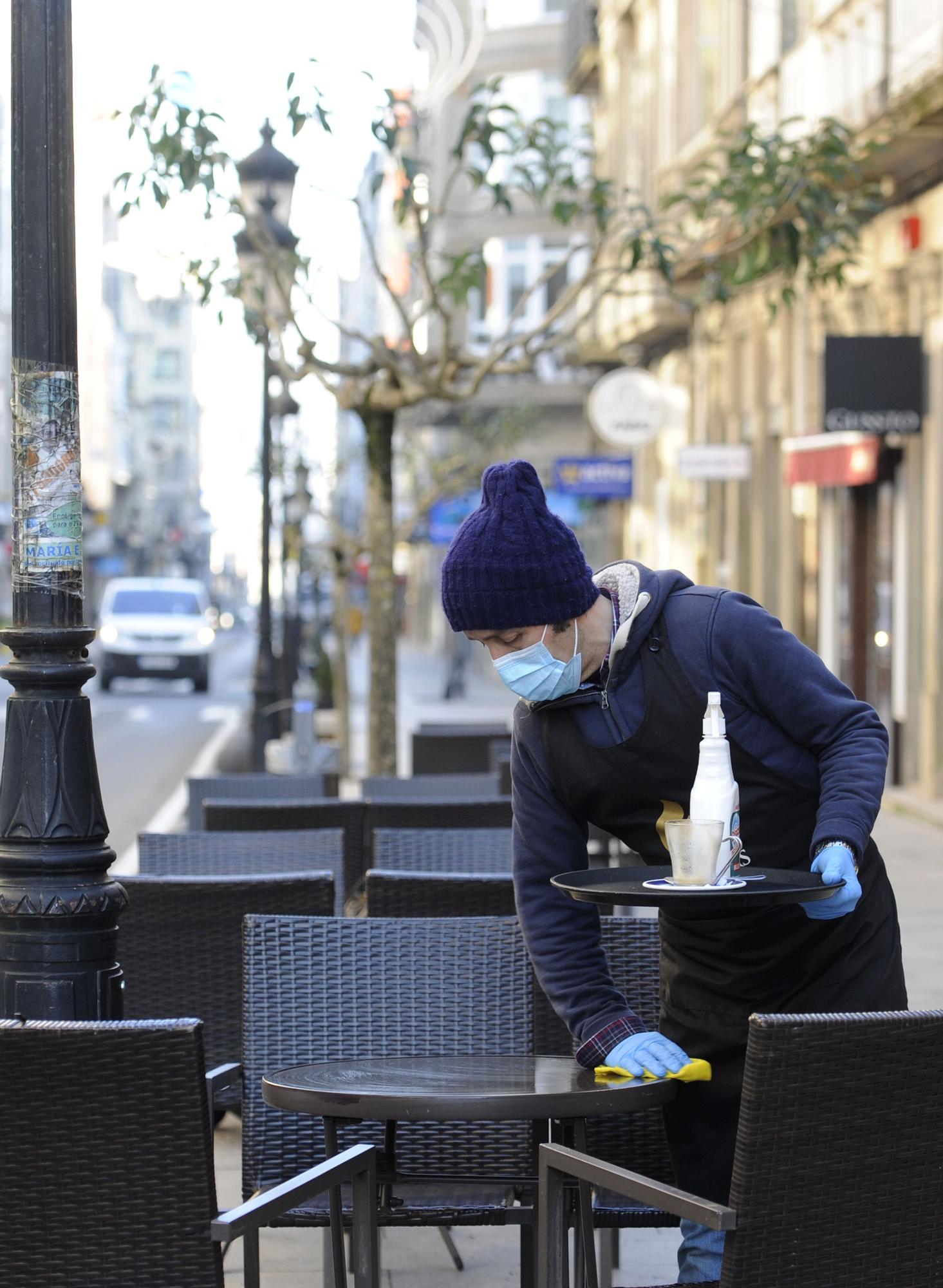 Un camarero desinfecta una mesa en una terraza. // Bernabé/Javier Lalín