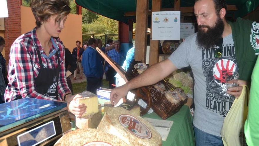 Verónica Blanco coloca sus quesos del valle mientras un visitante degusta un trozo.