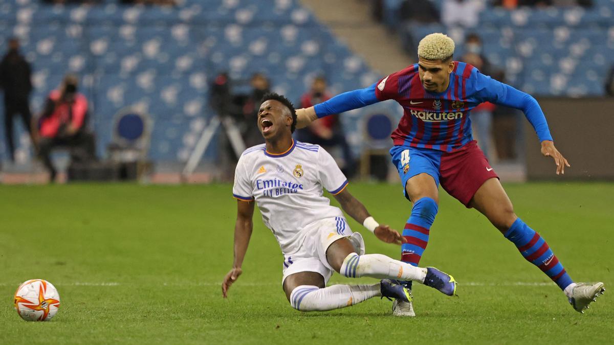 Barcelona's Uruguayan defender Ronald Araujo (R) goes for a tackle against Real Madrid's Brazilian forward Vinicius Junior during the Spanish Super Cup semi-final football match between Barcelona and Real Madrid at the King Fahad International stadium in the Saudi capital Riyadh on January 12, 2022. (Photo by FAYEZ NURELDINE / AFP)