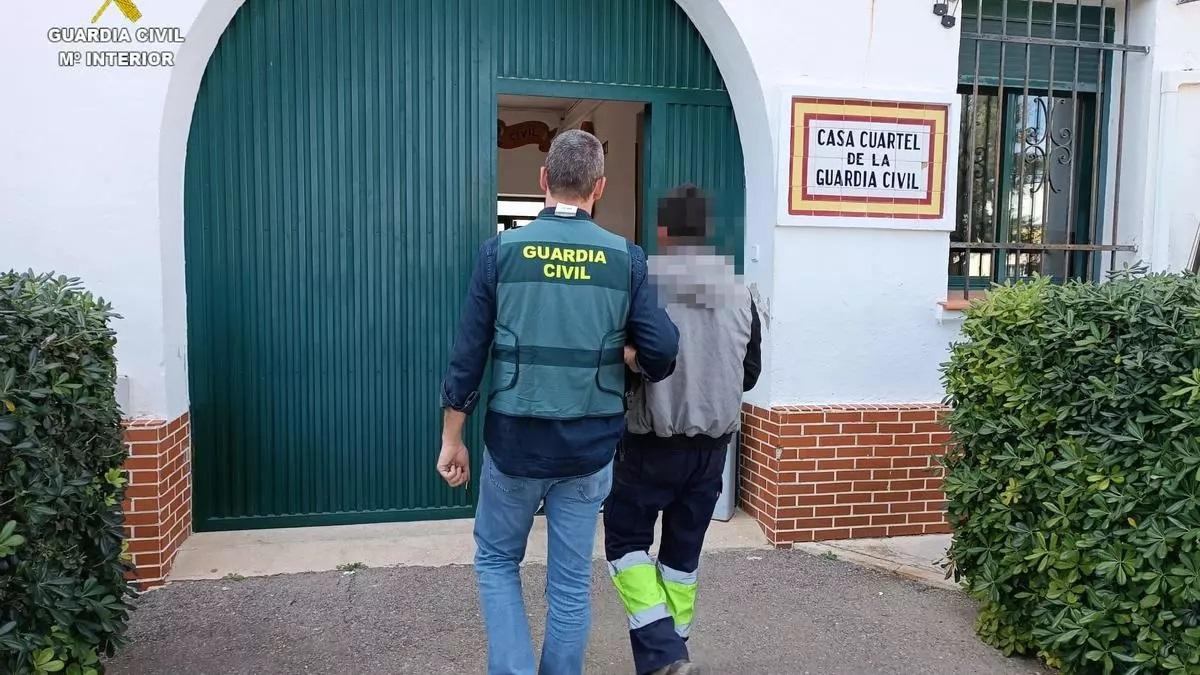 Una gente de la Guardia Civil conduce a un detenido a los calabazos de Benigànim.