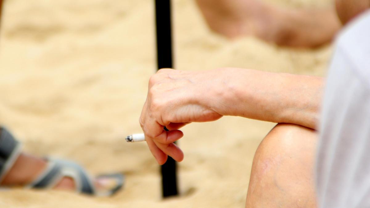 Una dona subjecta un cigarro mentre conversa amb informadors a la platja de la Nova Icària