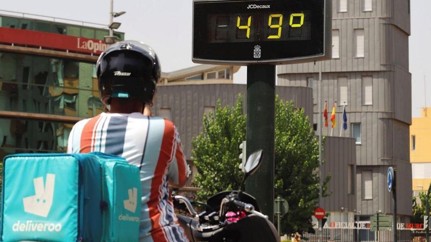 Un repartidor de menjar a domicili davant un termòmetre que marca 49ºC al sol | EFE