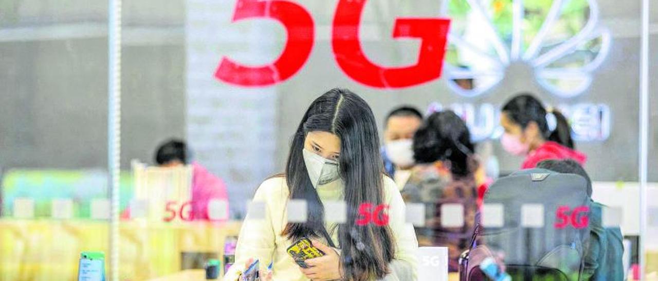 Una mujer examina telefónos en una tienda de Huawei |
