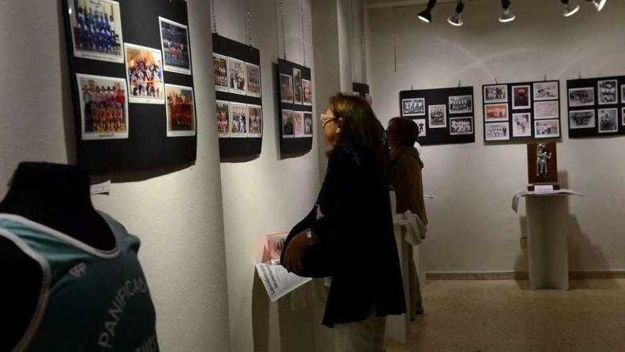 Asistentes a la exposición observan las distintas fotografías del baloncesto lenense.