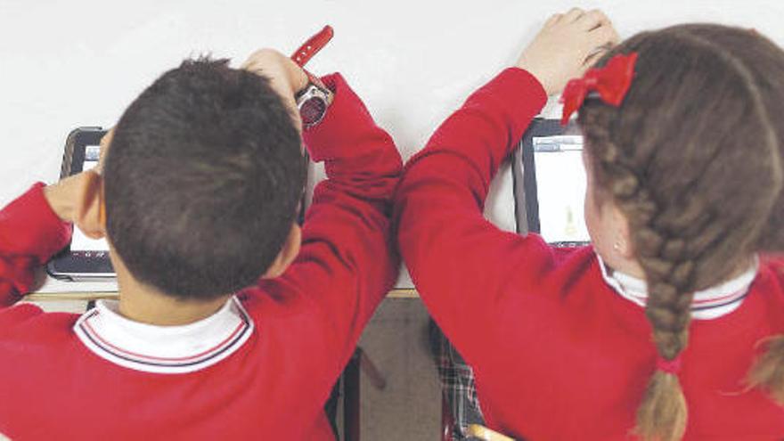 Dos alumnos de Educación Primaria estudian con una tableta sentados en su aula .