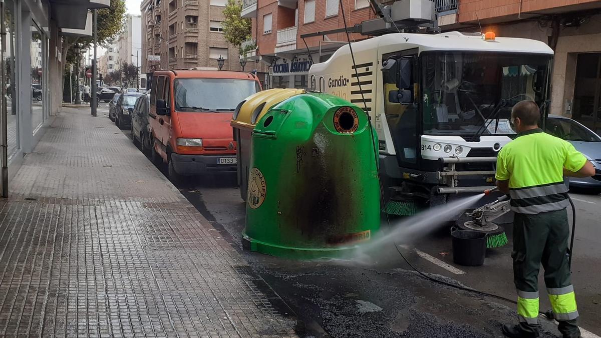 Un operario limpia una isla de contenedores de residuos en la ciuda de Gandia.