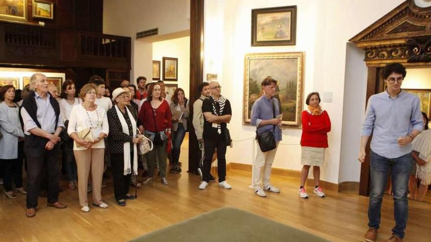 Arriba, asistentes a la visita guiada al Evaristo Valle, con Lamadrid a la derecha. A la izquierda, una mujer, ante dos cuadros del artista. Bajo estas líneas, fósiles y conchas de la colección del padre del pintor expuestos en el museo.