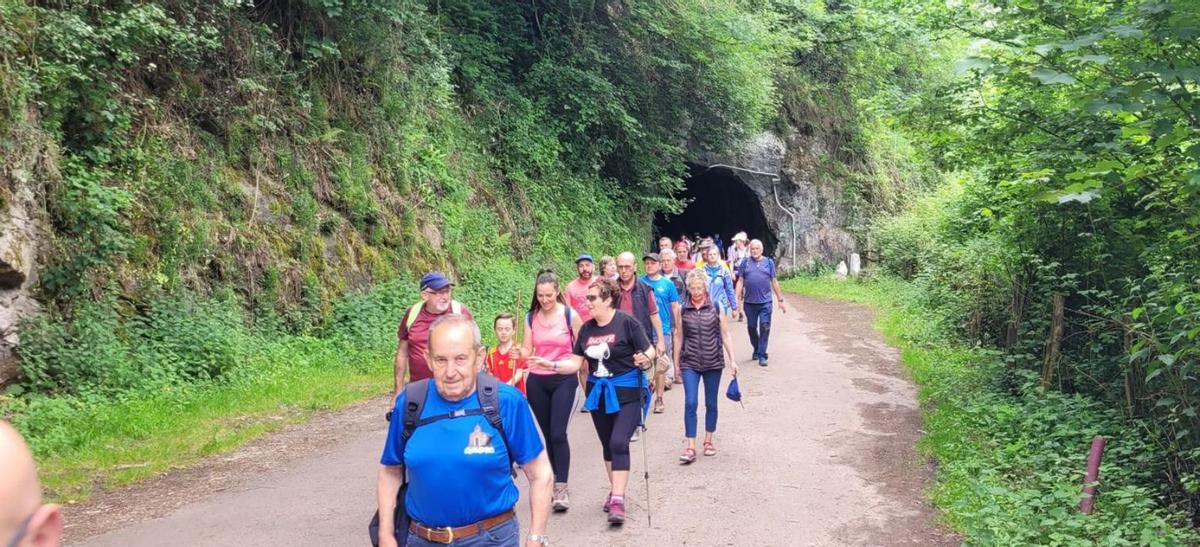 Los senderistas tras cruzar un túnel de la antigua vía del ferrocarril minero entre La Foz y La Pereda. | Fernando Delgado