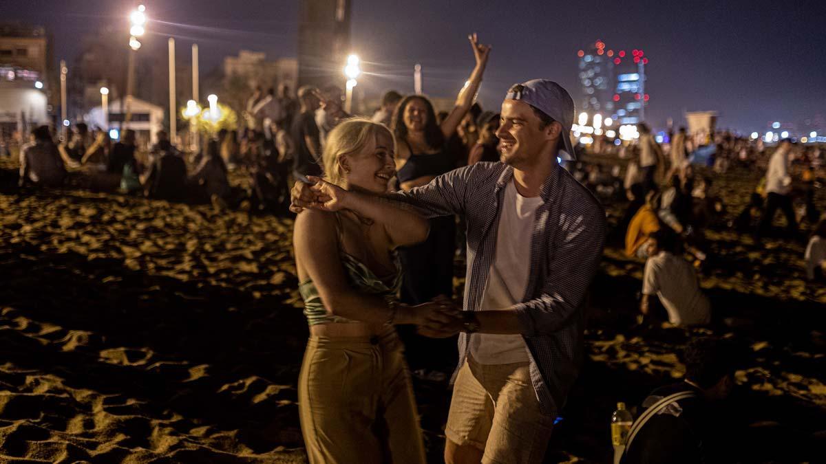 Una pareja baila mientras está de fiesta, de madrugada, en la playa de la Barceloneta.