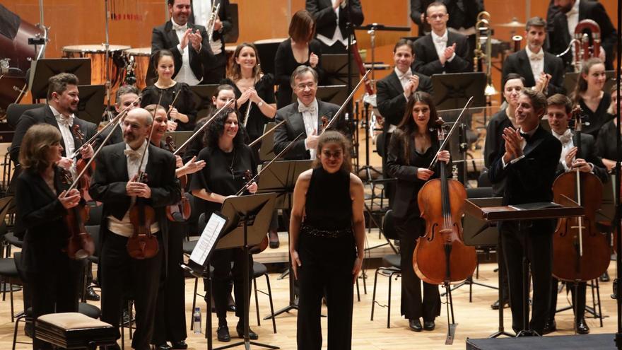 Arriba, la ovetense Raquel Rodríguez saluda ante el aplauso de Lucas Macías, a la derecha, y de la orquesta. Sobre estas líneas, el patio de butacas. | Juan Plaza