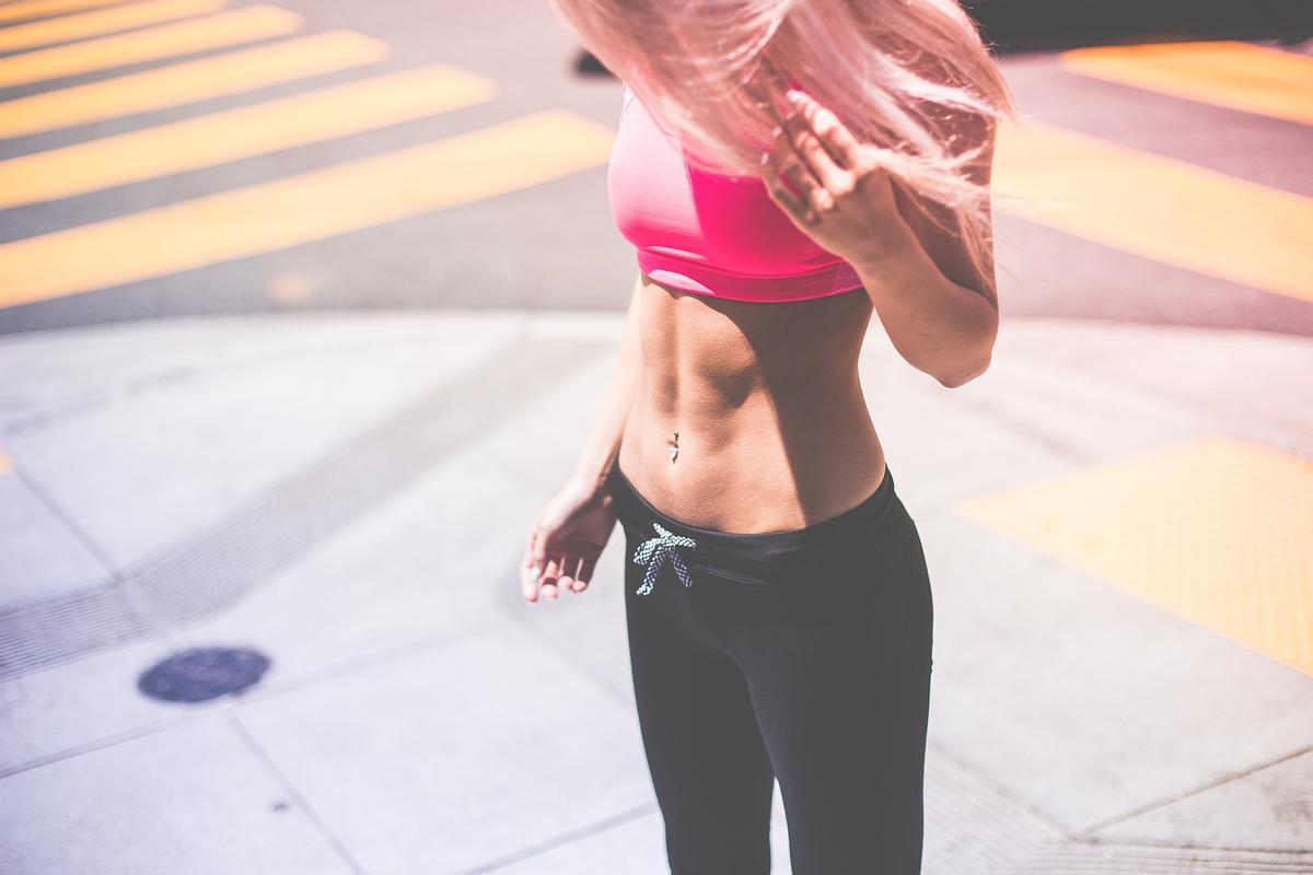 Una chica se mira el abdomen mientras hace deporte. 