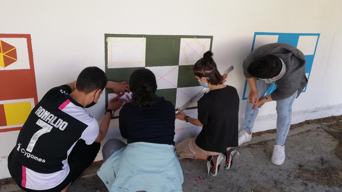 Los estudiantes pintando el bingo de fracciones en las paredes del recreo.