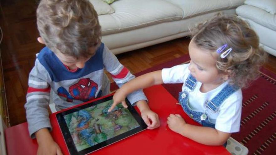 Dos niños pequeños exploran un juego en el iPad. //  A.P.