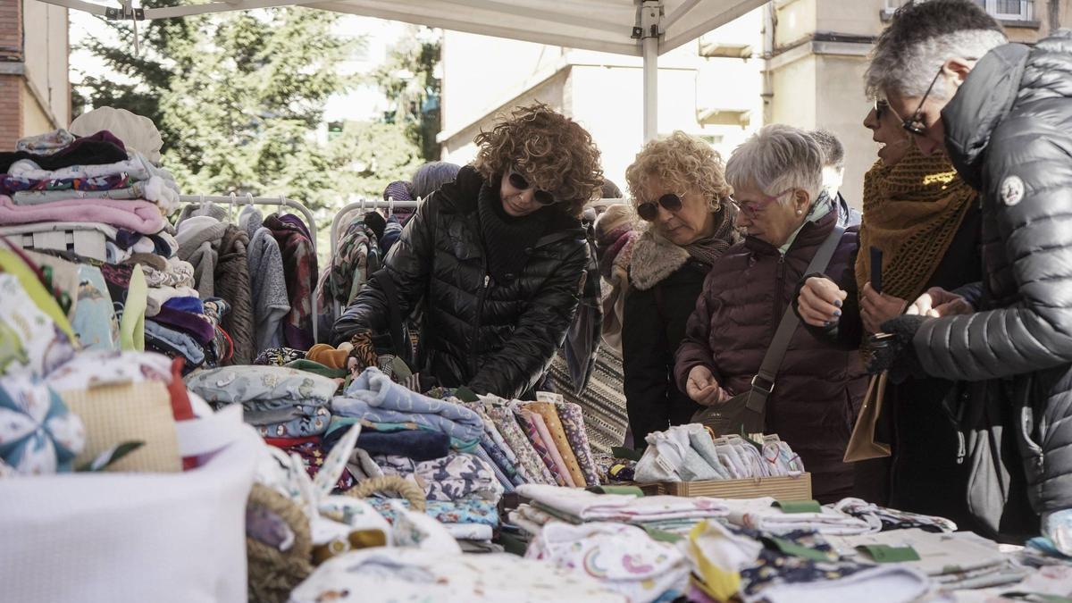 Visitants del mercat contemplen un estoc de roba d'una de les parades