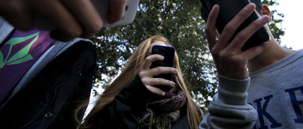 Adolescentes mirando sus teléfonos móviles.