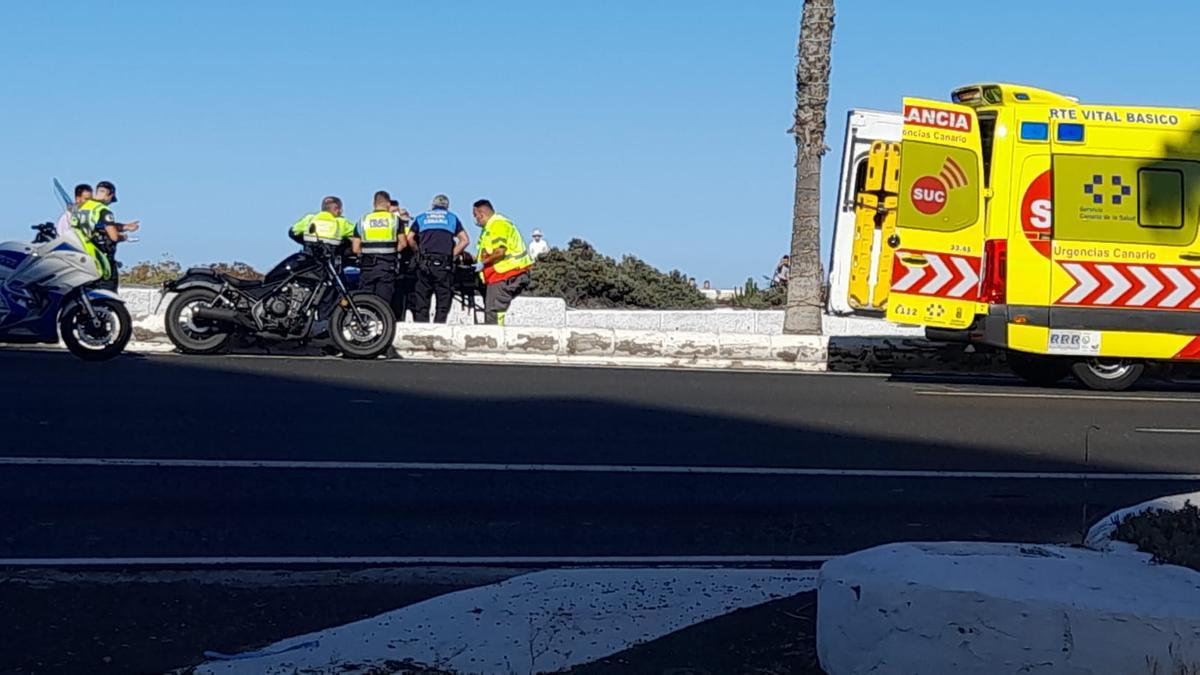 Policías locales y personal del SUC, este domingo, con la motorista accidentada, junto a su moto en la avenida marítima.