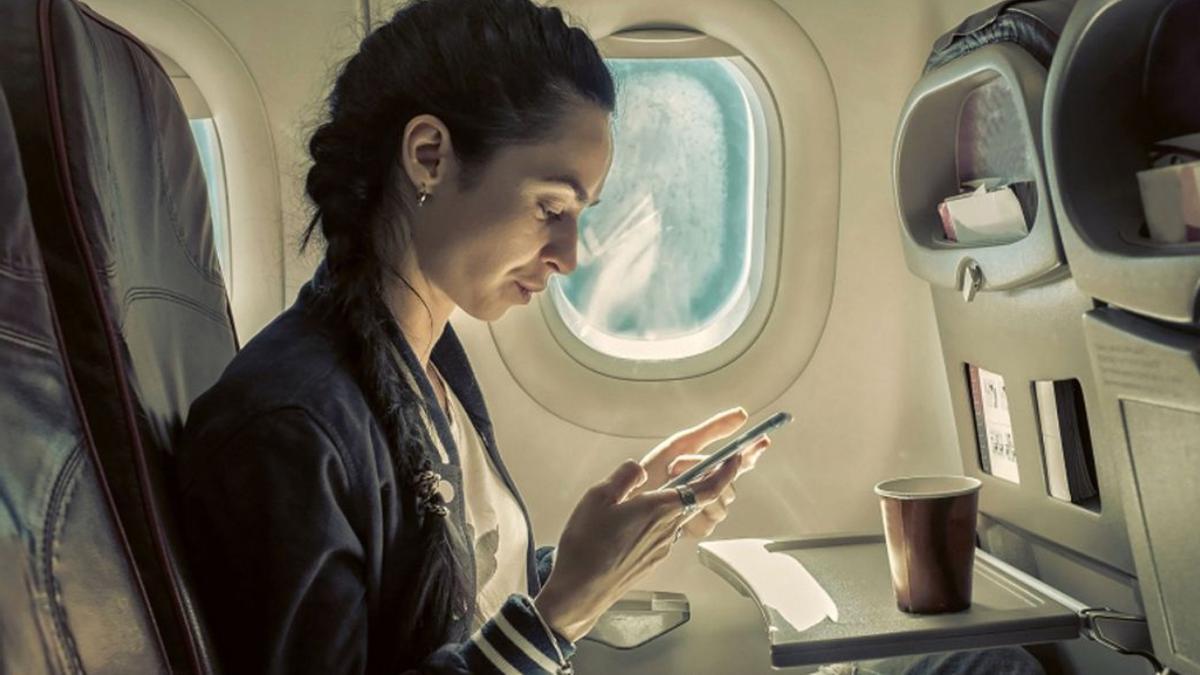 Una mujer con su móvil en un avión.