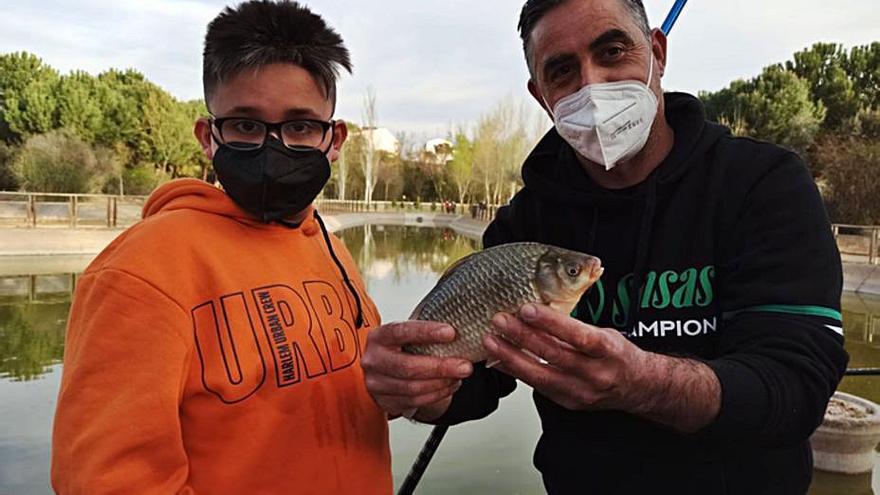 Uno de los monitores muestra uno de los peces capturados por el niño de la imagen, durante la práctica. | E. P.